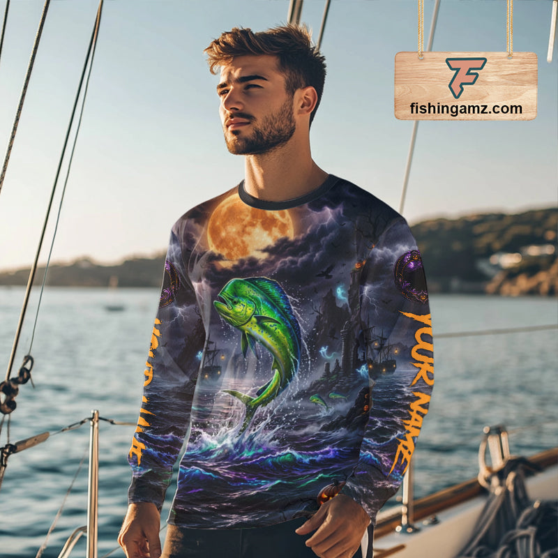 A long-sleeve crewneck shirt shown from both front and back, featuring an all-over Halloween-themed graphic print with a green jumping fish, dark stormy sky, orange full moon, ships, and orange vertical text on the sleeves.