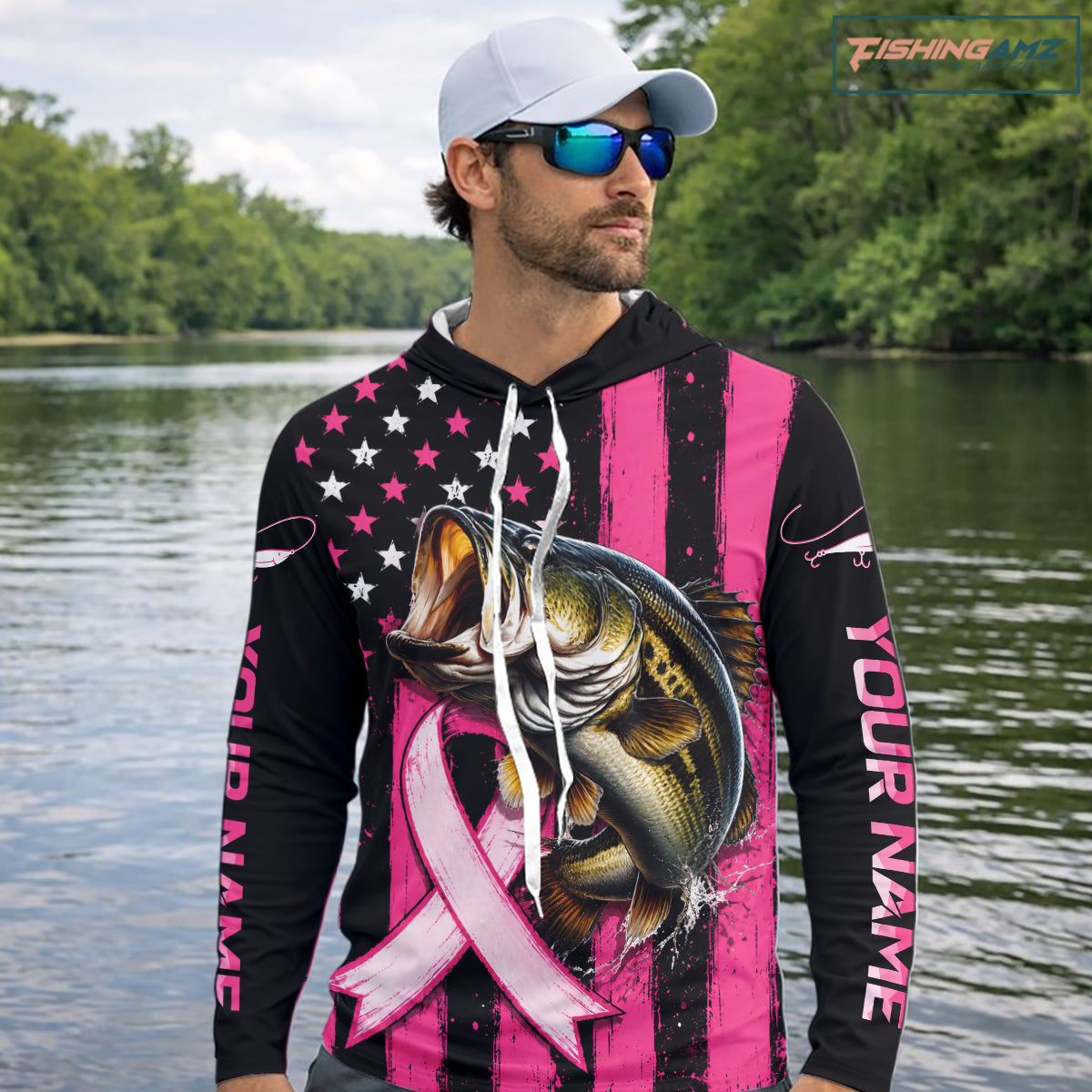 A man wearing a custom pink and black striped hoodie with a bass graphic, a pink ribbon, and 'YOUR NAME' printed on the sleeve, standing on a boat with fishing rods and the ocean in the background