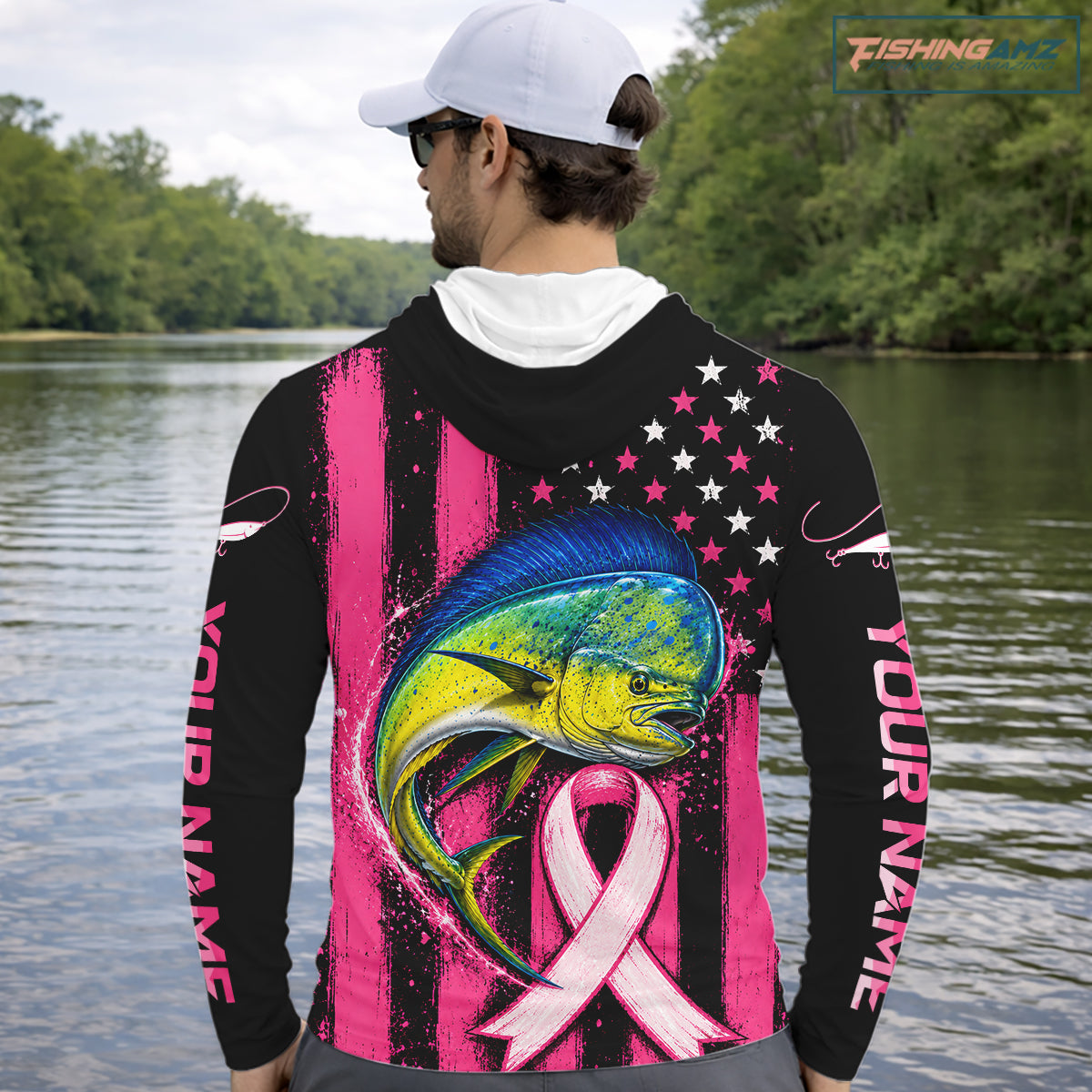 A man on a boat wearing a black and pink fishing hoodie with a large marlin graphic, pink awareness ribbon, and American flag pattern on the back. The hoodie has 'YOUR NAME' printed on the sleeve.