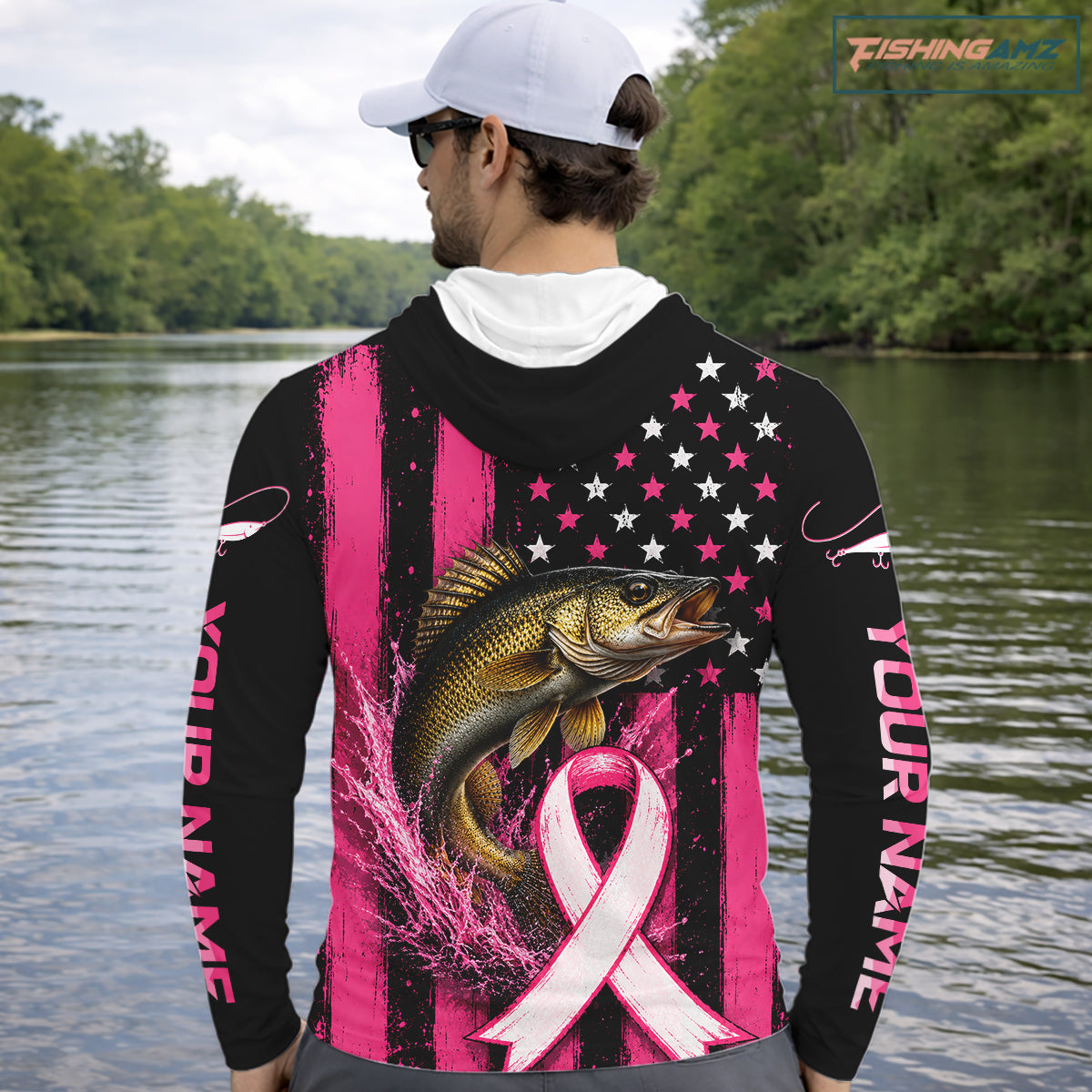 A man wearing a black and pink long-sleeve hoodie with a walleye fish graphic and pink ribbon design on the back, standing on a boat with fishing rods and the ocean in the background.