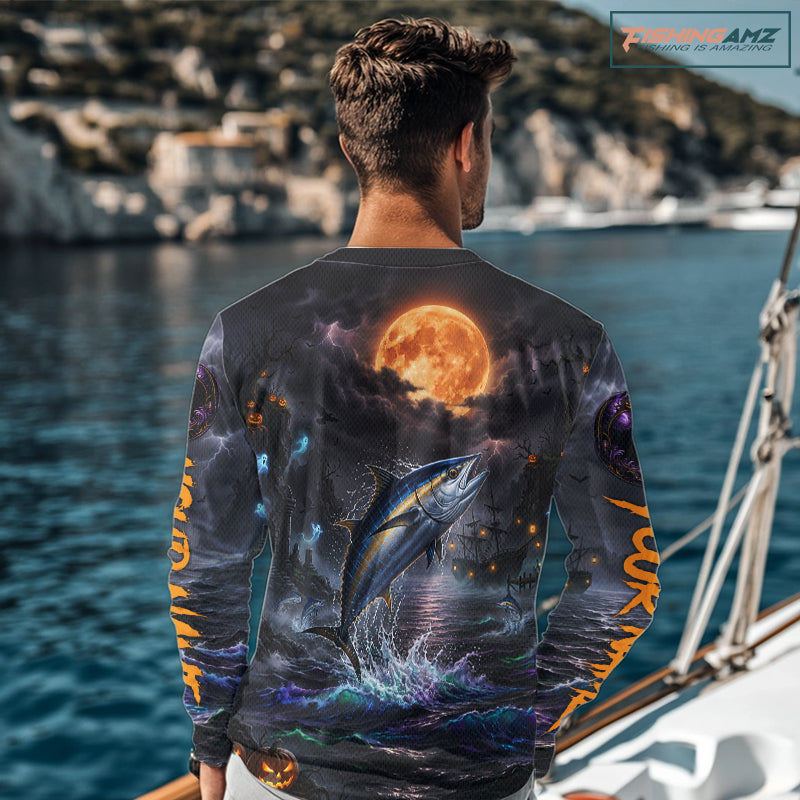 A man wearing a long-sleeve graphic shirt with a detailed print of a tuna fish leaping from the water under a full moon, set on a boat deck. A wooden sign with the text 'FishingAmz"