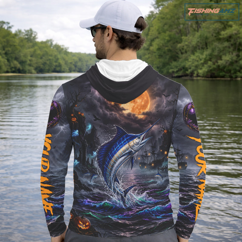 A man on a boat wearing a long-sleeve hoodie with a detailed all-over graphic print of a fish jumping from the water under a full moon, shown from the back.
