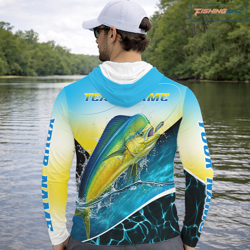 A man on a boat wearing a long-sleeve hooded fishing shirt with a large mahi-mahi fish graphic on the back and 'TEAM name' text across the shoulders. The shirt has a blue-to-yellow gradient with black and white details.