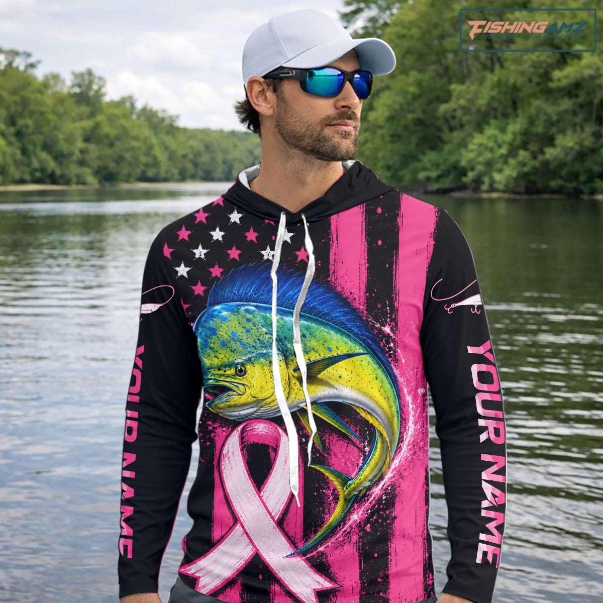 A man wearing a custom black and pink fishing hoodie with a large marlin graphic and pink awareness ribbon, standing on a boat with fishing rods and ocean in the background.